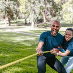 Engaged adults playing tug of war, showcasing teamwork and fun outdoors.
