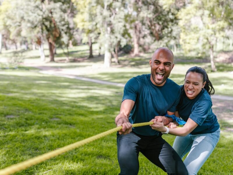 Engaged adults playing tug of war, showcasing teamwork and fun outdoors.